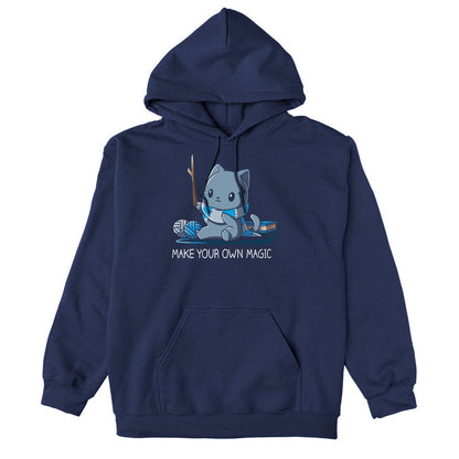 Pullover Hoodie_Teeturtle Make Your Own Magic Navy Blue Featuring a gray cat sitting in front of a book next to yarn with a wand-like stick and a crafted scarf with the text 'Make Your Own Magic' below.