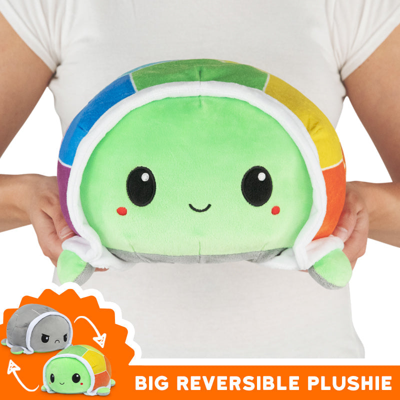 A woman holding a Big Reversible Turtle Plushie from TeeTurtle that brings joy.