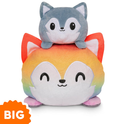 A patented Big Reversible Wolf plushie by TeeTurtle is stacked on top of another stuffed animal.