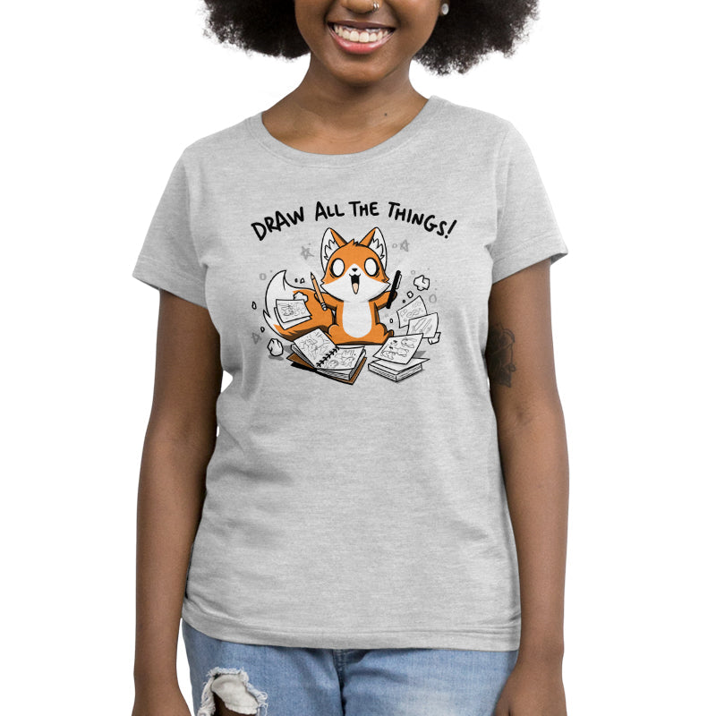 Premium Cotton T-shirt_A cartoon fox enthusiastically holding drawing tools, surrounded by sketchbooks with various drawings. Text above reads "Draw All The Things!" This monsterdigital original Draw all the Things! is crafted from super soft ringspun cotton for ultimate comfort.