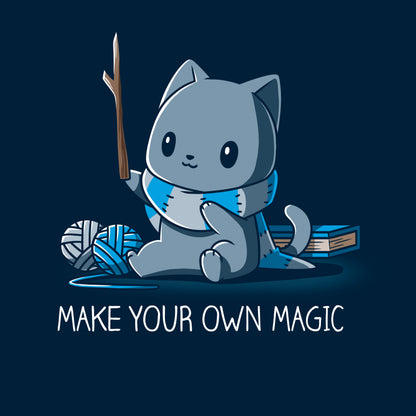 Classic Cotton T-shirt_Teeturtle Make Your Own Magic Navy Blue Featuring a gray cat sitting in front of a book next to yarn with a wand-like stick and a crafted scarf with the text 'Make Your Own Magic' below.