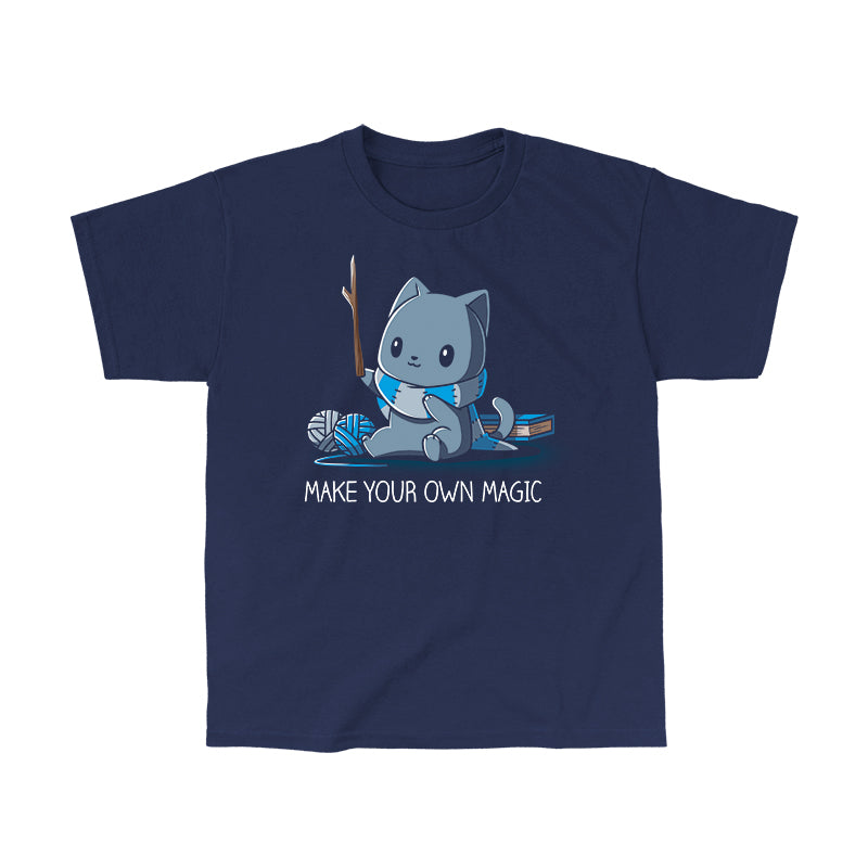 Classic Cotton T-shirt_Teeturtle Make Your Own Magic Navy Blue Featuring a gray cat sitting in front of a book next to yarn with a wand-like stick and a crafted scarf with the text 'Make Your Own Magic' below.