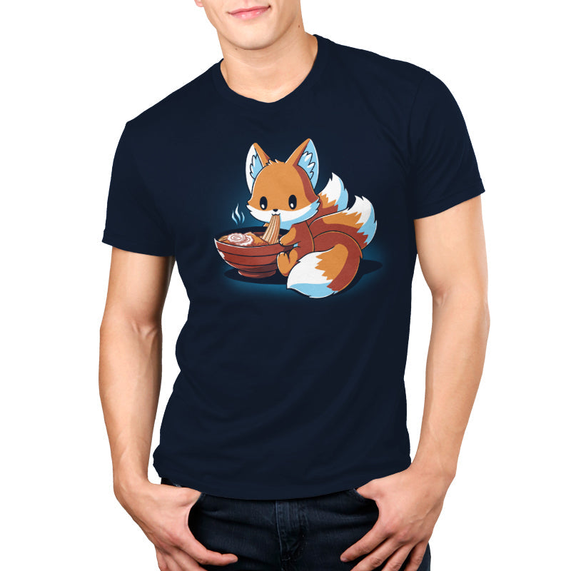 Premium Cotton T-shirt_A cartoon fox, known as the Ramen Kitsune, is sitting and eating noodles from a bowl, holding the noodles with its paws. Steam rises from the bowl. This charming scene is printed on a super soft ringspun cotton navy blue monsterdigital Ramen Kitsune apparel.