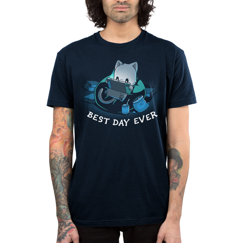 Premium Cotton T-shirt_TeeTurtle Best Day Ever navy blue t-shirt featuring an illustration of a cat sitting on a bean bag chair playing a portal video game surrounded by a mess of books and an open bag of chips and a can of soda with a straw. "BEST DAY EVER" is written underneath.