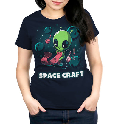 Premium Cotton T-shirt_TeeTurtle Space Craft navy blue t-shirt featuring an illustration of a green alien knitting a red scarf in space surrounded by planets, stars, balls of yarn, and a cup holding scissors, a paint brush and floating pencil. The words "SPACE CRAFT" are written below.