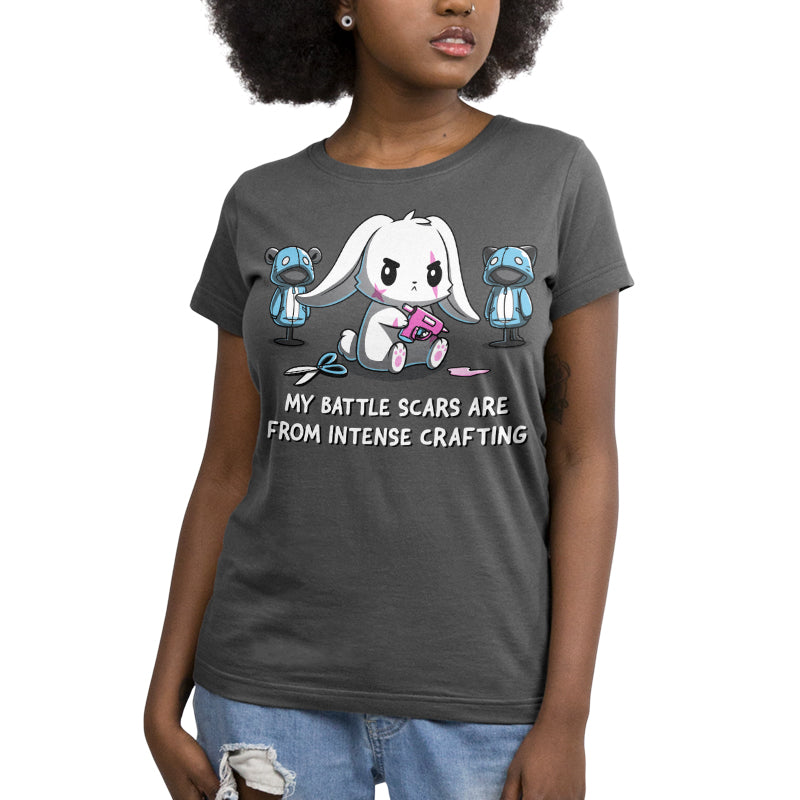 Premium Cotton T-shirt_TeeTurtle Battle Scars charcoal gray t-shirt featuring a determined cartoon rabbit holding a hot glue gun, surrounded by sewing supplies and mannequins, with the text "My battle scars are from intense crafting" below.