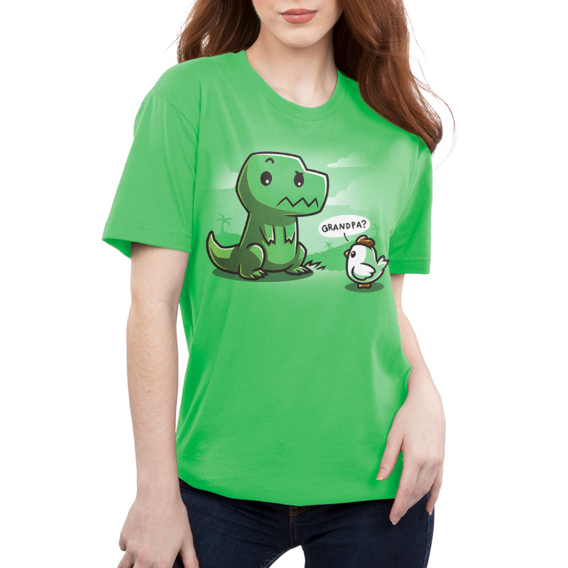 Premium Cotton T-shirt_Teeturtle Family Reunion apple green t-shirt   featuring a cartoon dinosaur with a puzzled expression sitting in front of a baby chick asking "Grandpa?" on a green background with faint scenery. 