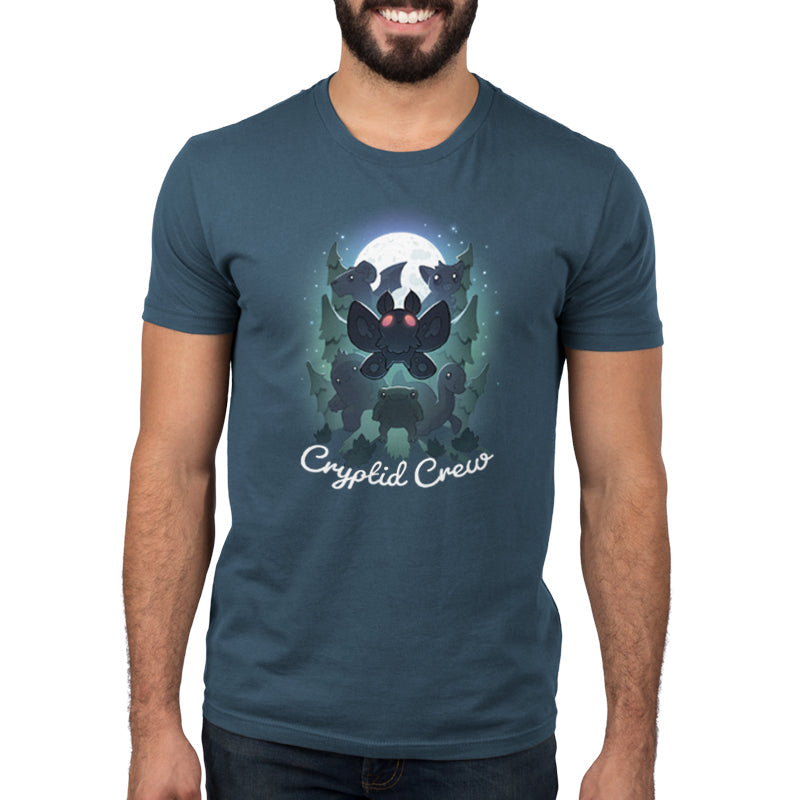 Premium Cotton T-shirt_TeeTurtle Cryptid Crew denim t-shirt featuring a whimsical illustration of six cartoon cryptids, including a mothman and a jackalope, in a forest with a full moon in the background. Text at the bottom reads "Cryptid Crew."