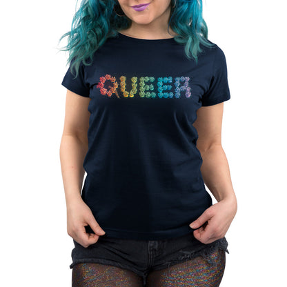 Premium Cotton T-shirt - Person with teal hair wears a navy blue apparel made of super soft ringspun cotton with the words "Queer and Proud" by monsterdigital in a rainbow floral pattern and black shorts.