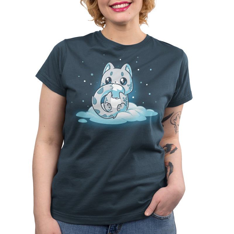 Premium Cotton T-shirt_TeeTurtle Snuggly Snow Leopard Denim t-shirt featuring a cartoon-style baby snow leopard with large eyes sitting on a cloud, hugging its tail, against a dark background with falling snowflakes. 