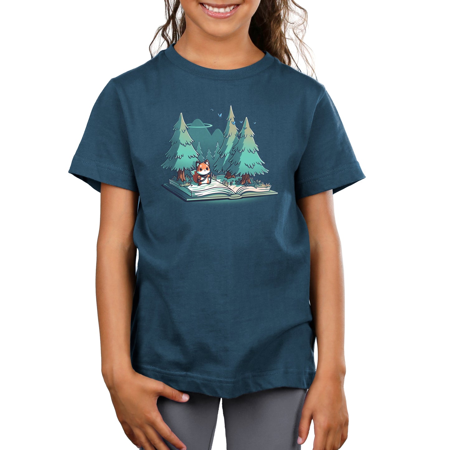 Premium Cotton T-shirt_TeeTurtle  Adventurer's Tale Denim Blue t-shirt features an enchanting illustration of a fox standing on an open book transformed into a forest, with trees and mountains in the background.