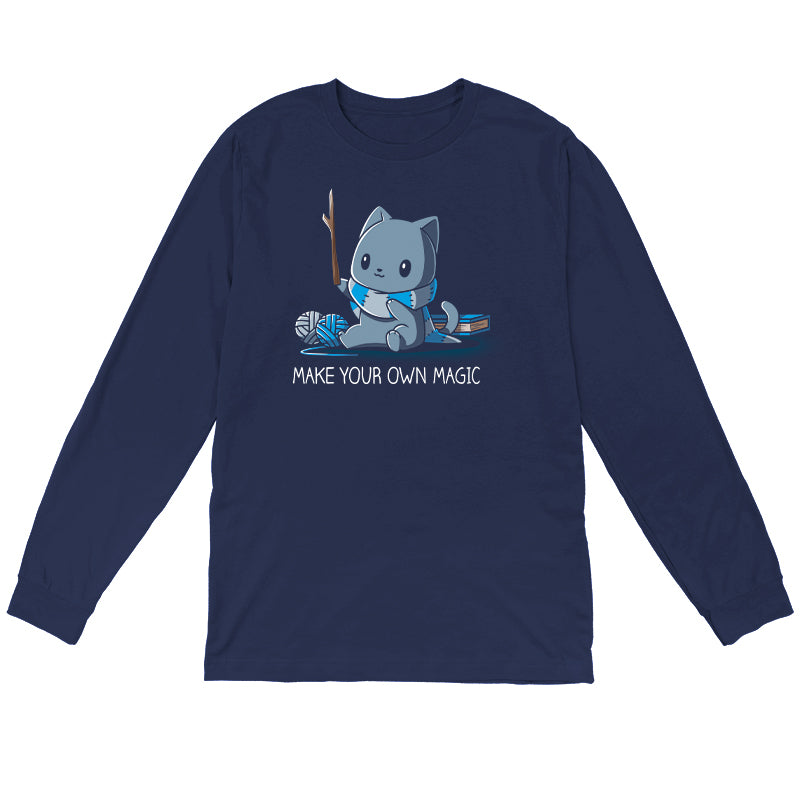 Long Sleeve T-shirt_Teeturtle Make Your Own Magic Navy Blue Featuring a gray cat sitting in front of a book next to yarn with a wand-like stick and a crafted scarf with the text 'Make Your Own Magic' below.