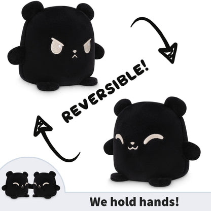 Two black bears from TeeTurtle, the Reversible Bear Plushmates from TeeTurtle, intimately hold hands while being plush toys.