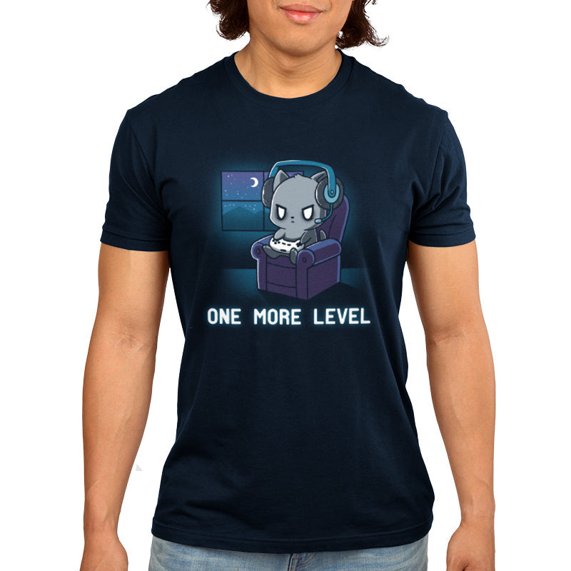 Premium Cotton T-shirt_Teeturtle One More Level navy blue t-shirt featuring a cat wearing headphones, holding a game controller, and sitting in a chair with a nighttime window view. Text below reads "One More Level."