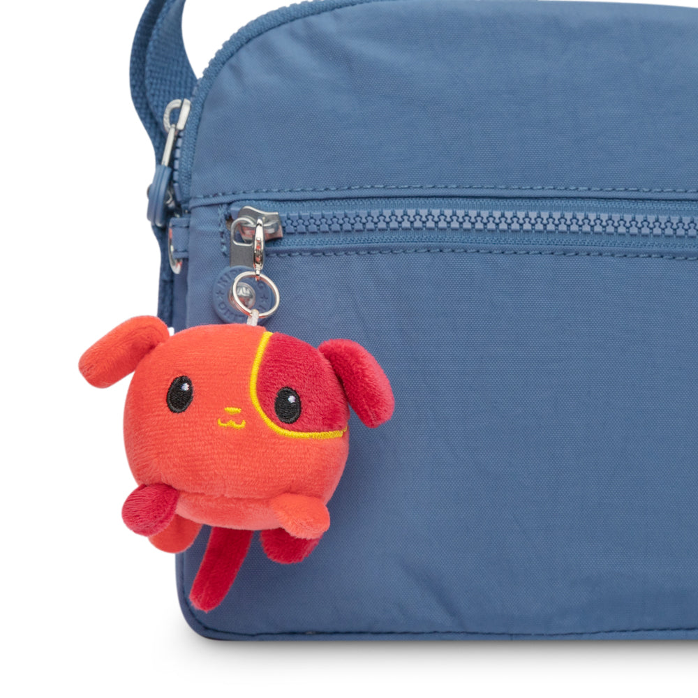 A portable blue bag with a Lunar New Year Dog Plushie Charm Keychain from TeeTurtle hanging from it.