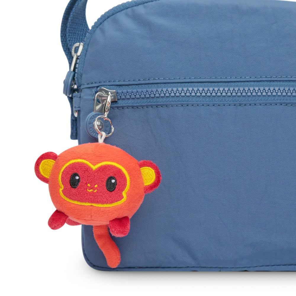 A blue purse with a TeeTurtle Lunar New Year Monkey Plushie Charm Keychain attached to it, part of the Lunar New Year collection.