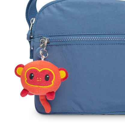 A blue purse with a TeeTurtle Lunar New Year Monkey Plushie Charm Keychain attached to it, part of the Lunar New Year collection.