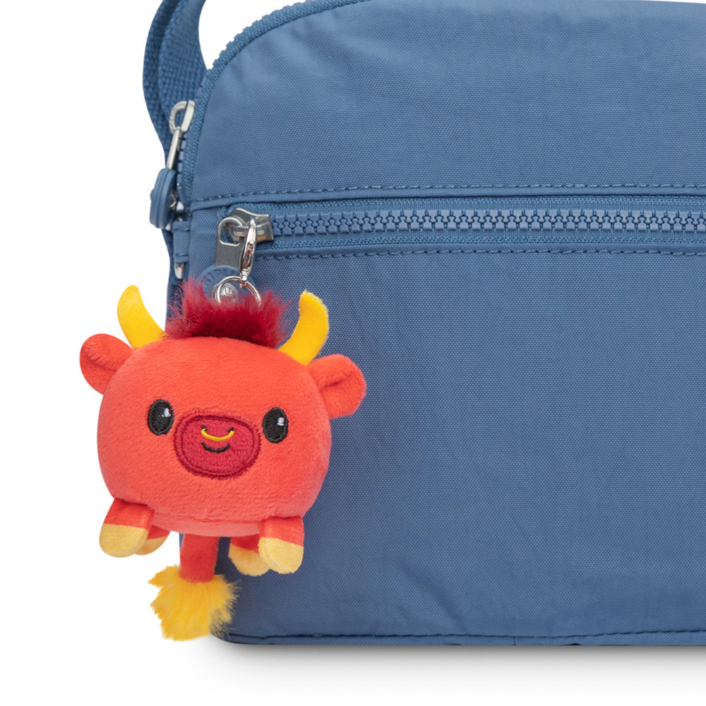 A Lunar New Year Ox Plushie Charm Keychain from TeeTurtle is attached to the side of a blue bag, perfect for Lunar New Year celebrations.