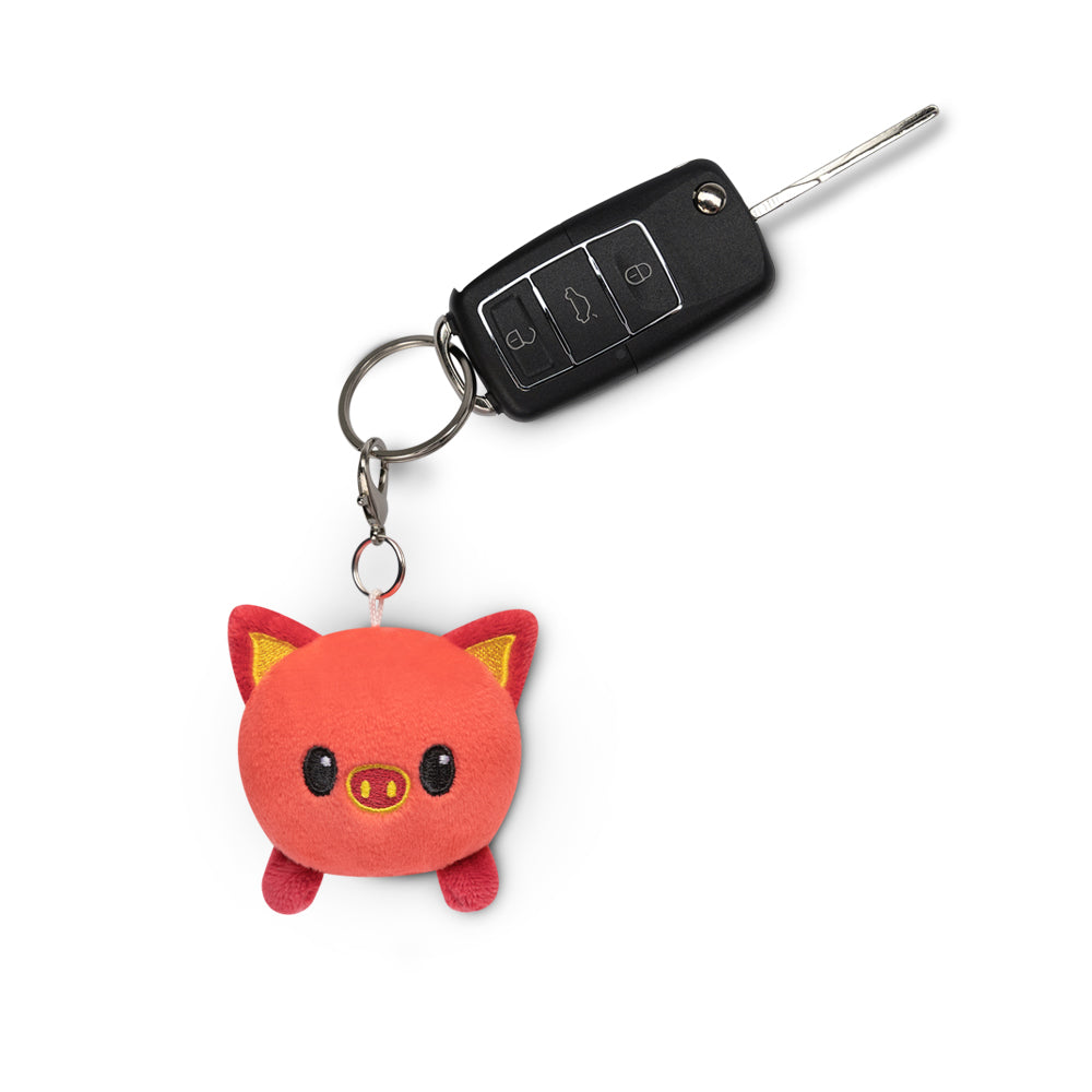 A Lunar New Year-themed Lunar New Year Pig Plushie Charm Keychain featuring a pig, perfect for backpacks or adding a touch of cuteness to any accessory by TeeTurtle.