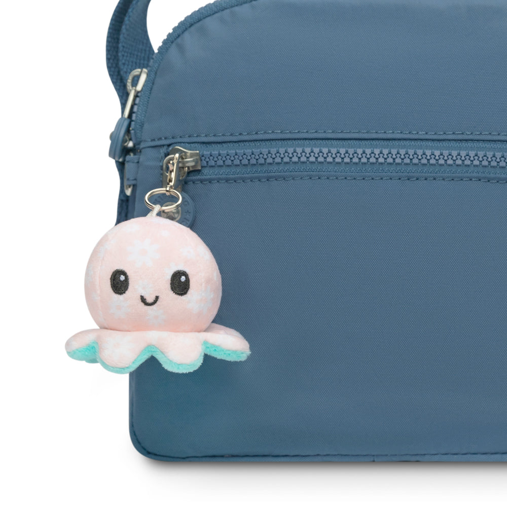 A blue purse with a pink TeeTurtle Octopus Plushie Charm Keychain attached.