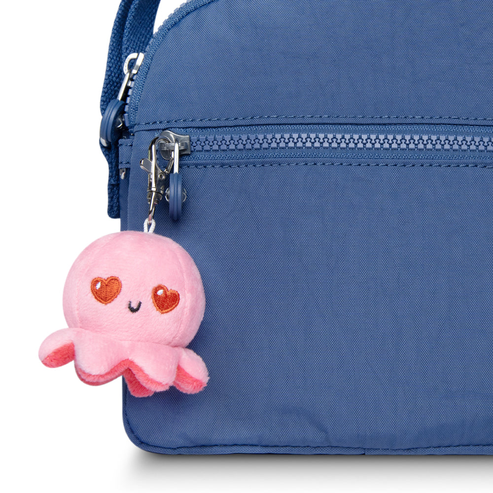 A blue purse with a TeeTurtle pink Octopus Plushie Charm Keychain accessory.