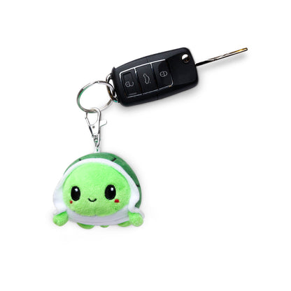 A portable Turtle Plushie Charm Keychain with a car key attached to it made by TeeTurtle.