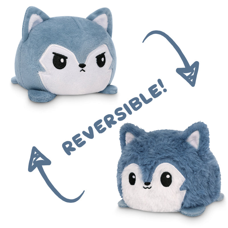 A **TeeTurtle Reversible Wolf Plushie (Fuzzy Gray)** from **TeeTurtle** that changes from a grumpy blue fox to a happy blue fox, shown with arrows indicating the reversible feature and the word "REVERSIBLE!" in between. Mood plushies that switch emotions with ease!