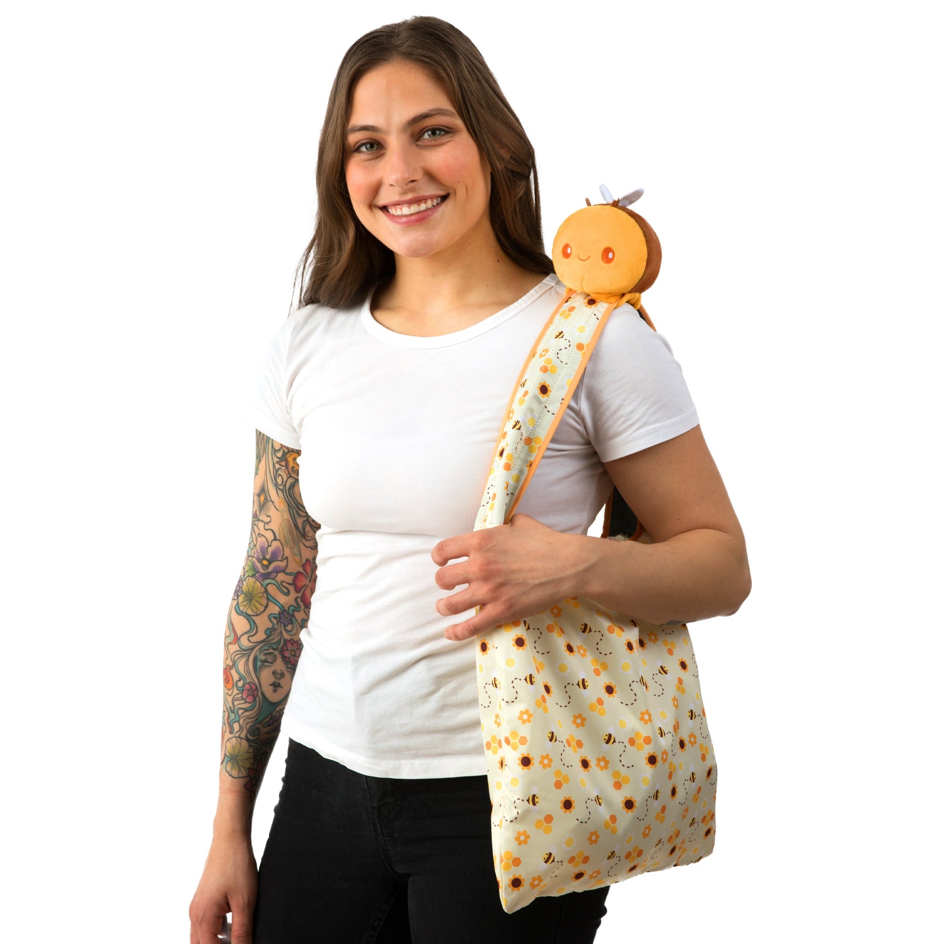 A woman with TeeTurtle's Honeycomb Bee Plushie Tote Bag and tattoos holding a velcro storage pouch.