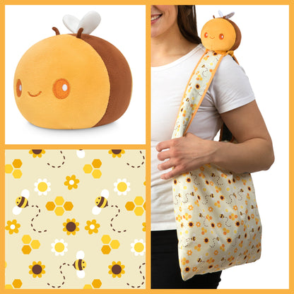 A woman is holding a TeeTurtle Honeycomb Bee Plushie Tote Bag.