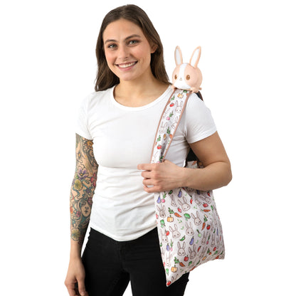 A woman holding a TeeTurtle Plushiverse Farmer's Market Bunny Plushie Tote Bag.