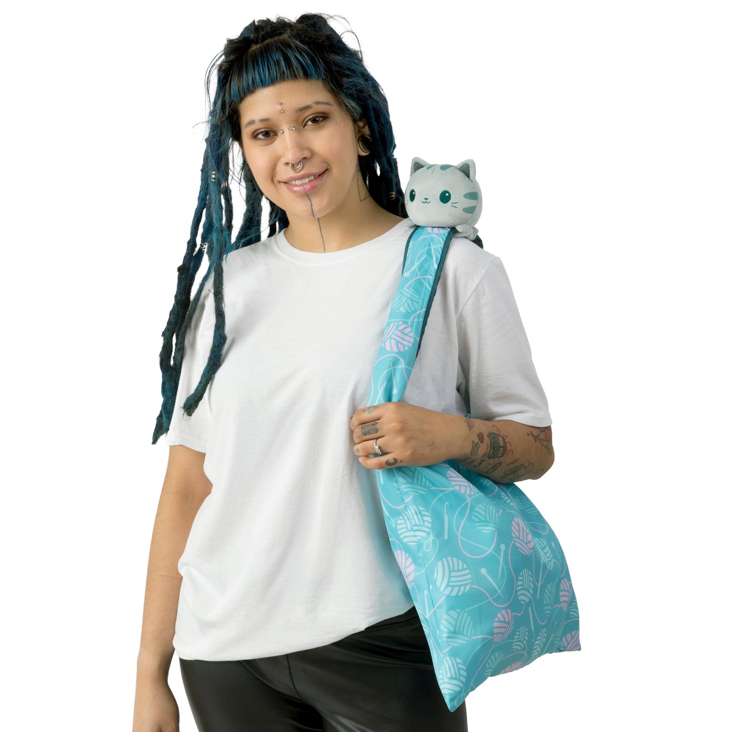 A woman holding a blue tote bag with a TeeTurtle Crafting Cat Plushie Tote Bag on it.