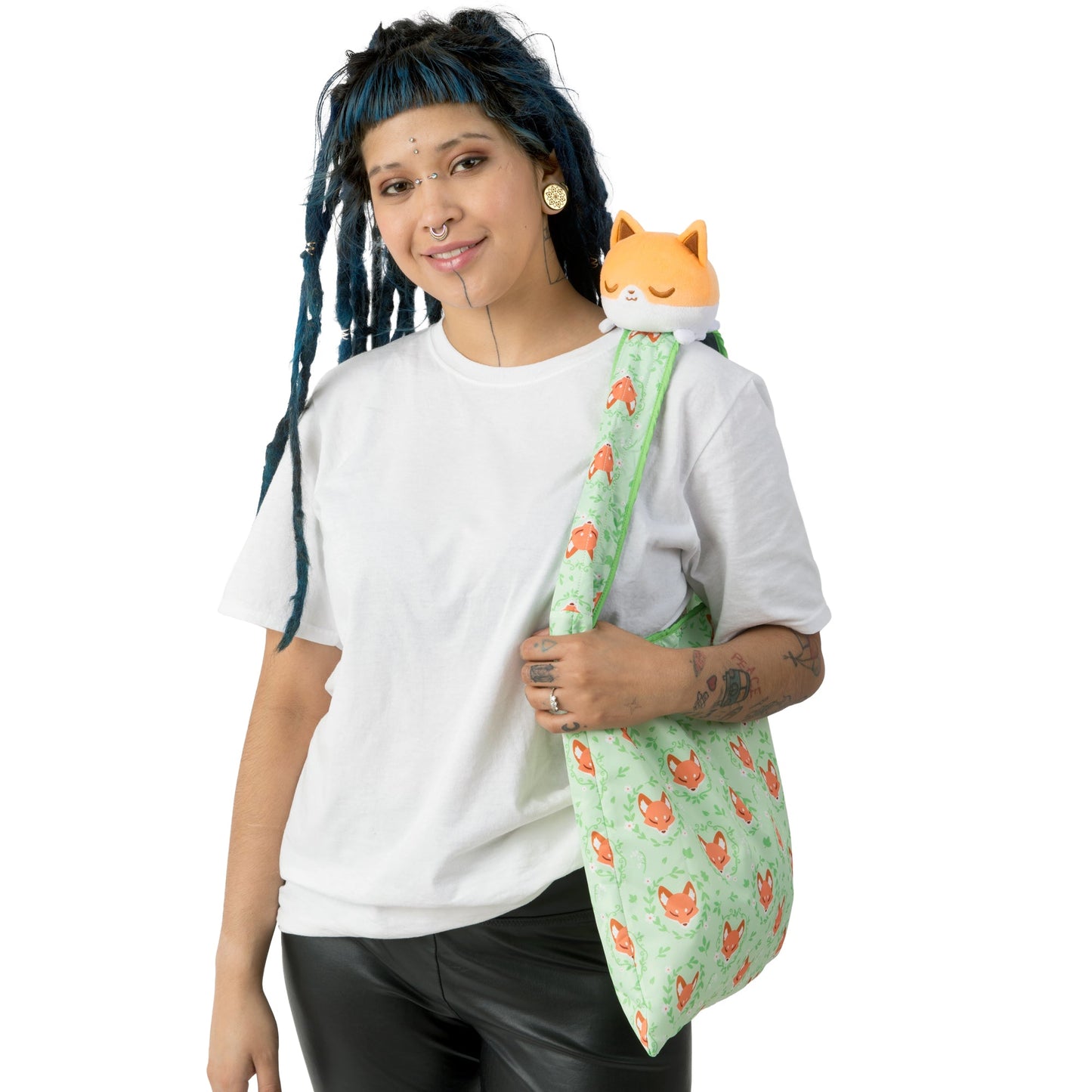 A woman with dreadlocks holding a TeeTurtle Floral Fox Plushie Tote Bag with a stuffed fox plushie.