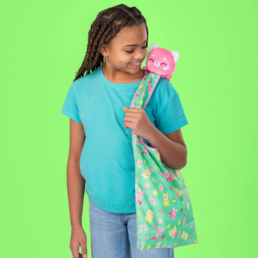 A girl holding a TeeTurtle Plushiverse Strawberry Lemonade Red Panda Tote Bag with a plushie inside.