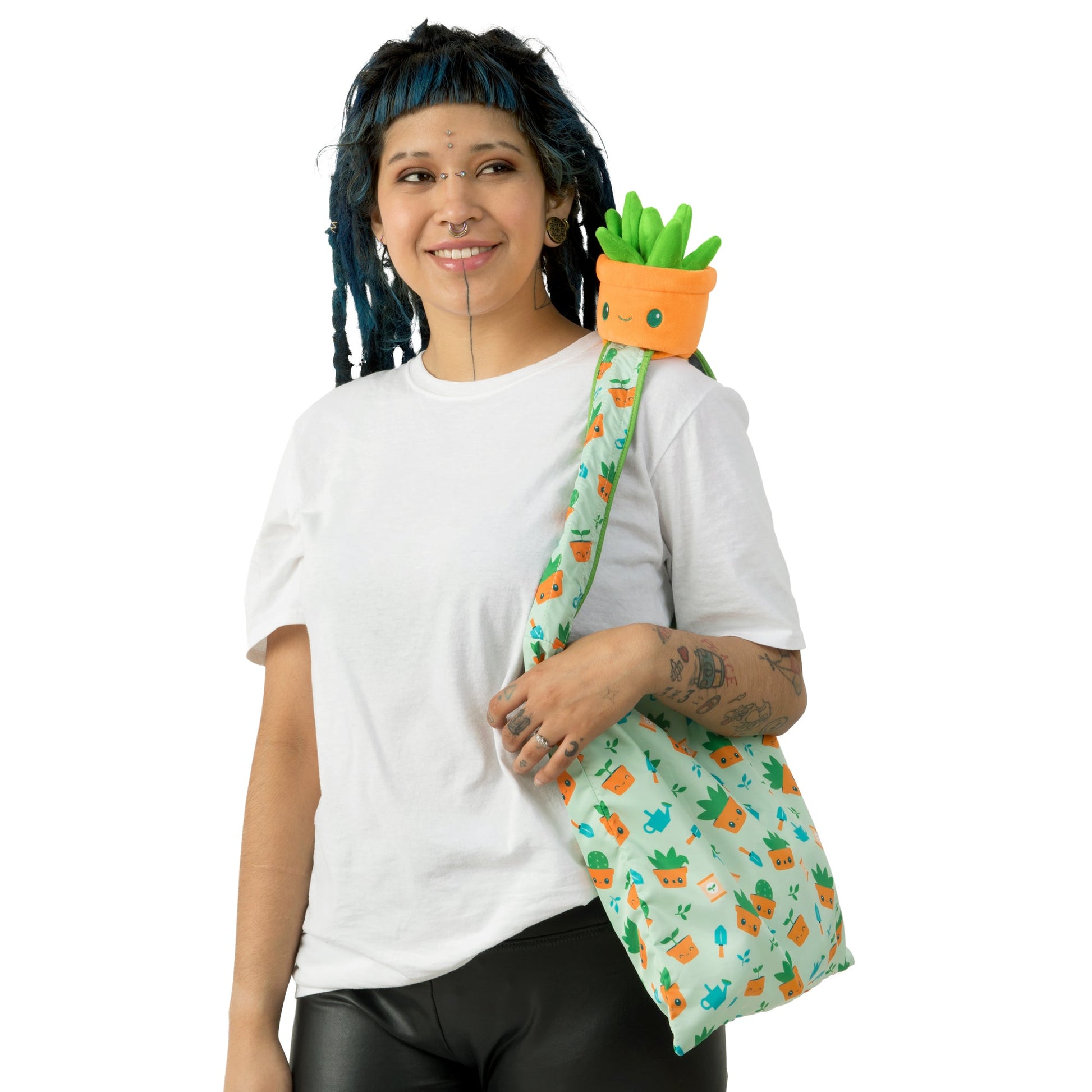 A woman with dreadlocks carrying a secret TeeTurtle Gardening Succulent Plushie Tote Bag.