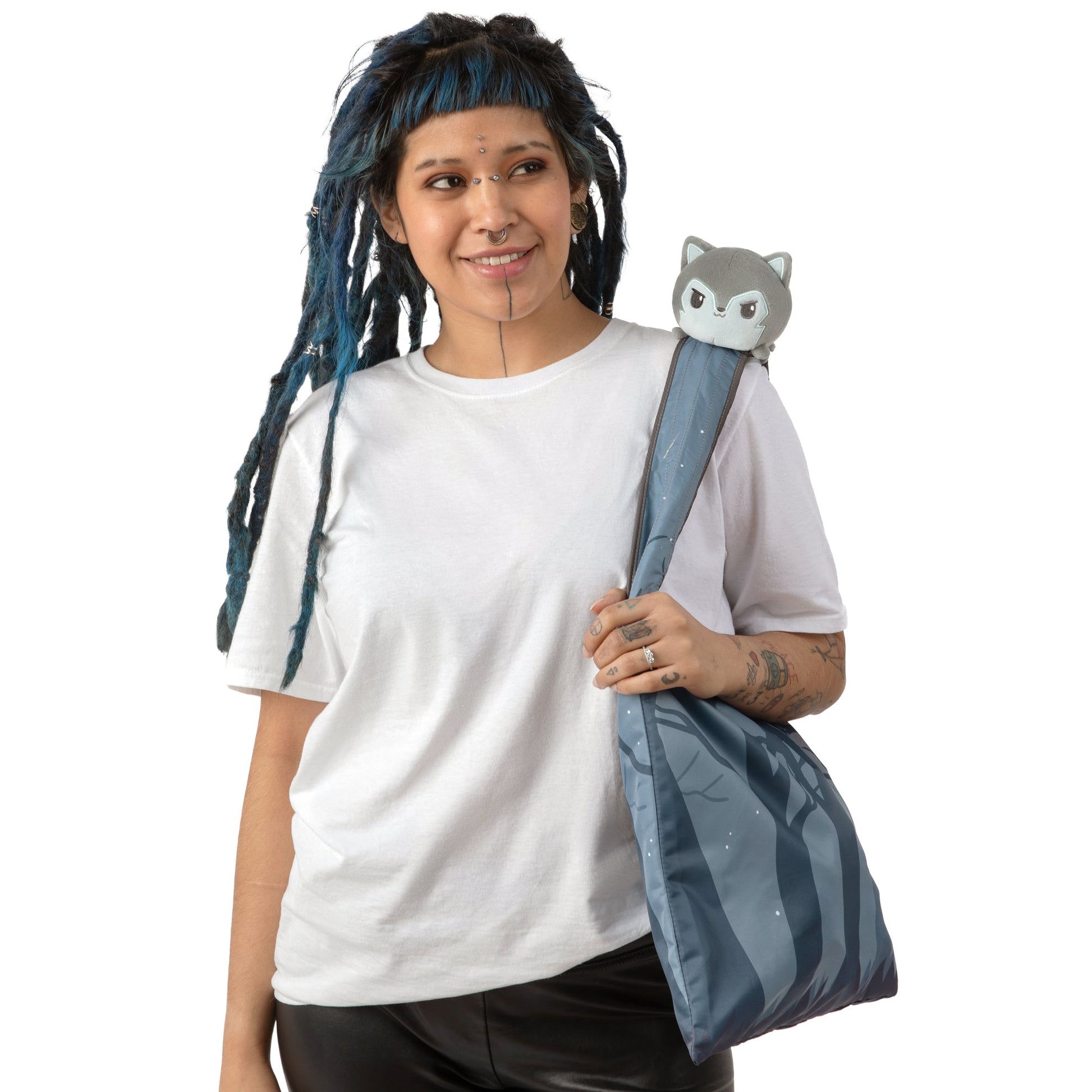 A woman with dreadlocks holding a TeeTurtle Forest Wolf Plushie Tote Bag.