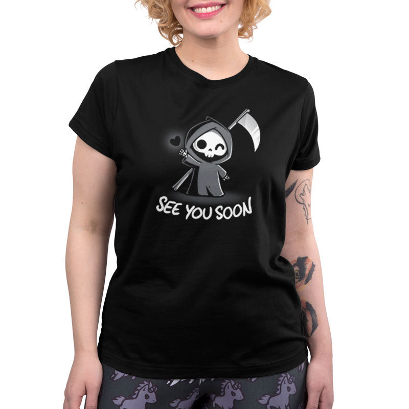 Premium Cotton T-shirt_TeeTurtle See You Soon black t-shirt featuring a spooky cartoon Grim Reaper holding a scythe, waving, and a floating black heart next to it, with the text below that says in dark humor "SEE YOU SOON". 