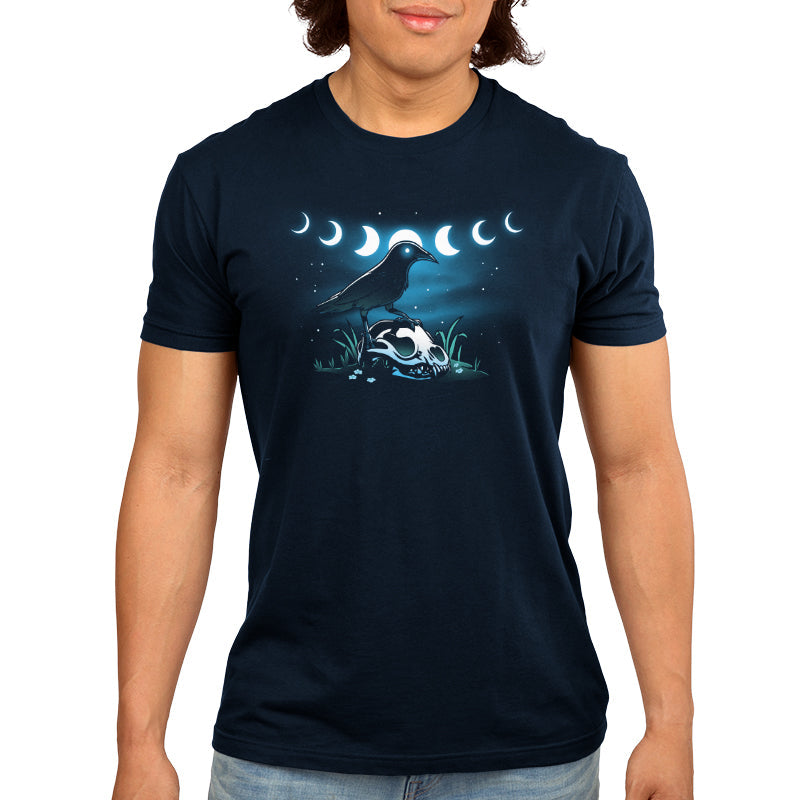 Premium Cotton T-shirt_TeeTurtle Mystical Crow navy blue t-shirt featuring a crow with glowing eyes standing on an animal skull in a grassy area under a night sky.