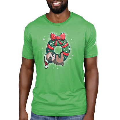 Premium Cotton T-shirt_TeeTurtle We Wish You a Lazy Christmas apple green t-shirt featuring a cartoon sloth in a Santa hat, snoozing while hanging from a festive wreath adorned with red ribbons and ornaments. 