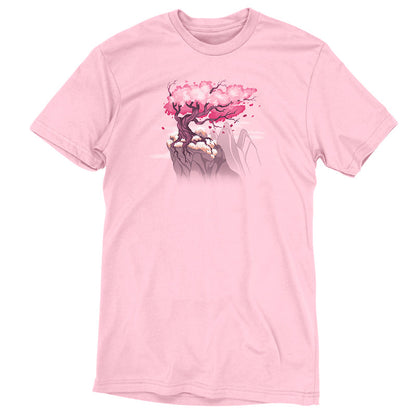 Premium Cotton T-shirt_TeeTurtle Sakura Tree pink t-shirt featuring an illustration of a pink cherry blossom tree on a rocky cliff with mountains in the background. Blossoms and petals are being blown in the wind. 