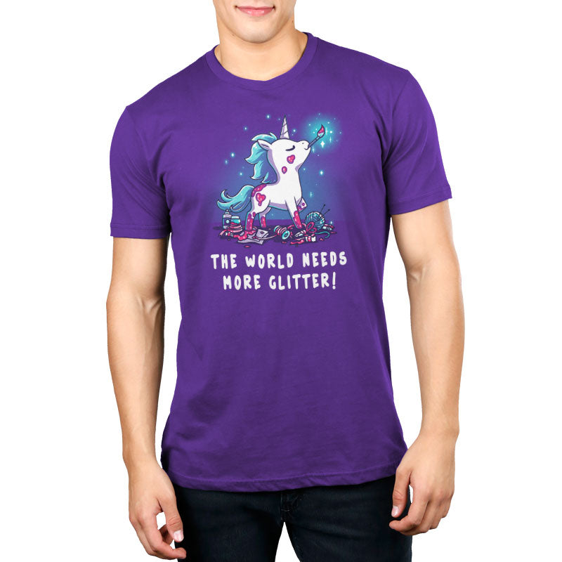 Premium Cotton T-shirt_TeeTurtle The World Needs More Glitter Purple t-shirt featuring a white unicorn holing a paint brush in it's mouth with a blue mane and tail, standing proudly above an assortment of craft supplies. It's covered with patches of pink glitter, one of which is shaped like a heart. Beneath it are the words "THE WORLD NEEDS MORE GLITTER!"