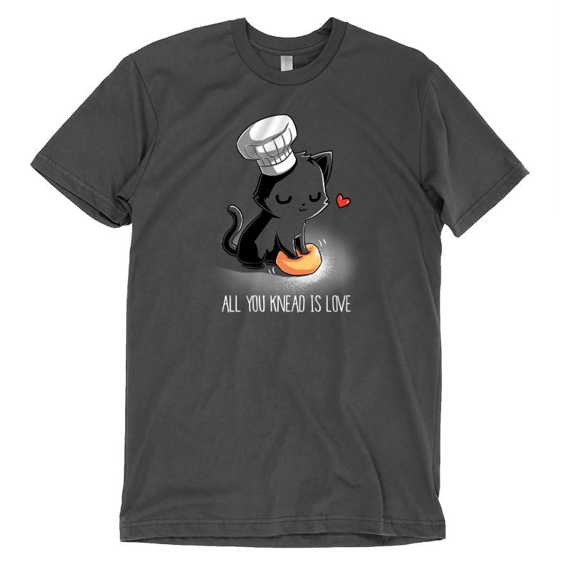 Premium Cotton T-shirt_A cartoon black cat wearing a chef's hat kneads a dough ball, with a red heart above its head, on this unisex tee. Caption reads: "All You Knead Is Love". Made of super soft ringspun cotton, this charcoal gray apparel called "All You Knead Is Love" by monsterdigital is perfect for cat lovers and baking enthusiasts alike.