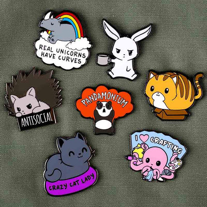 A set of TeeTurtle enamel pins with different animals on them, including care instructions, including the Real Unicorns Have Curves Pin.