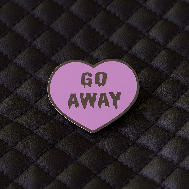 An Enamel Pin featuring a pink heart with the words "go away" on it, crafted from Metal and Enamel. It is the TeeTurtle Go Away Pin.