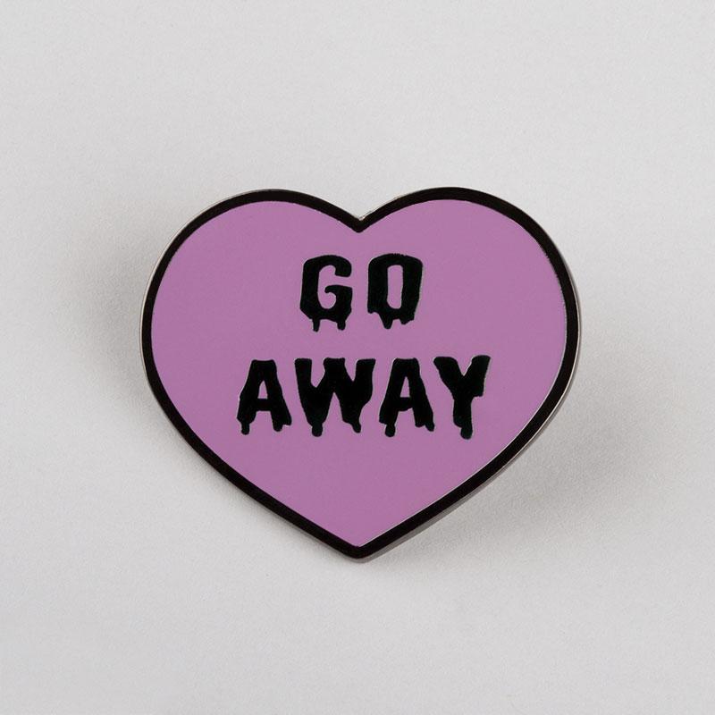 An Go Away Pin enamel pin featuring a purple heart with the words "go away" that can be wiped clean, made by TeeTurtle.