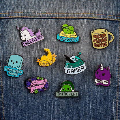 A collection of TeeTurtle's Need More Coffee Pins displayed on a denim jacket.